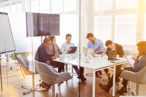 Six people at a business meeting around a conference table