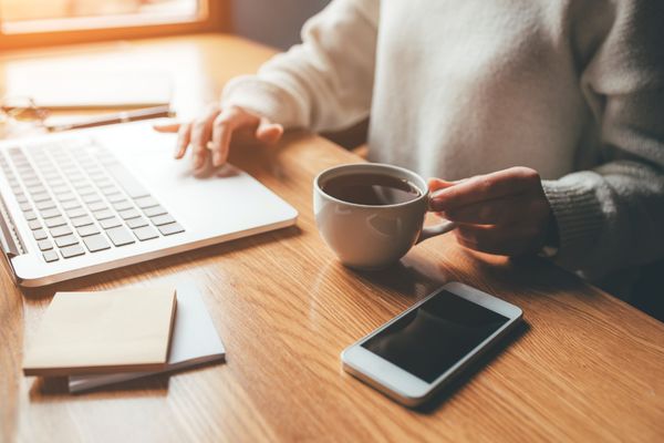 Woman at desk working on laptop with a cup of coffee