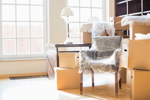 Interior of house with moving boxes and wrapped furniture